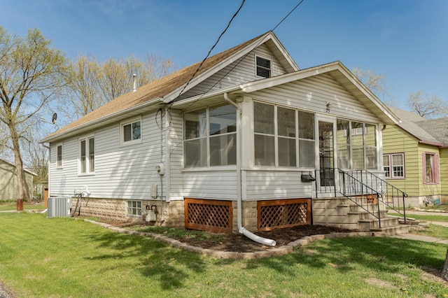 back of house with a lawn, a sunroom, and central AC