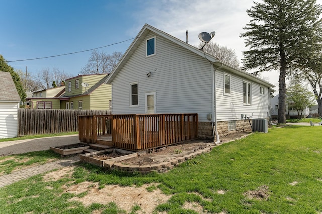 rear view of property with a lawn, fence, a wooden deck, and cooling unit