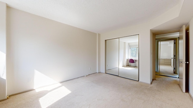 unfurnished bedroom with light colored carpet and a closet