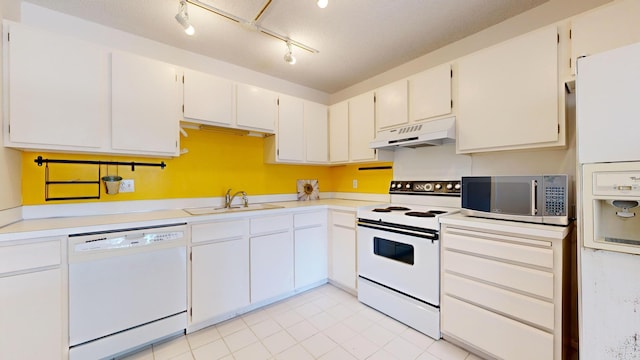 kitchen with white appliances, under cabinet range hood, a sink, light countertops, and light tile patterned flooring