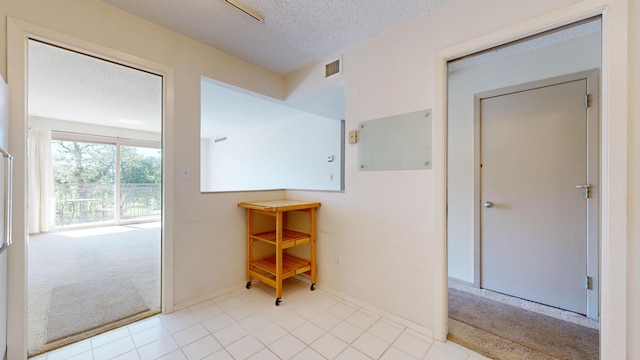 hallway with carpet flooring, baseboards, a textured ceiling, and tile patterned flooring