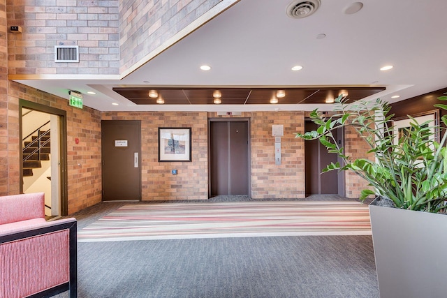 lobby featuring brick wall, recessed lighting, and stairs