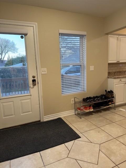 doorway with baseboards and light tile patterned flooring