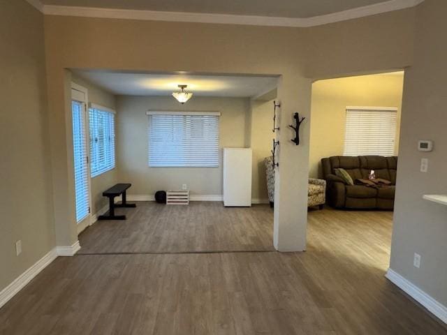 interior space with baseboards, ornamental molding, and wood finished floors