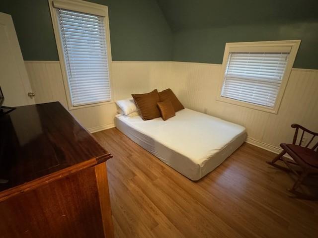 bedroom with wainscoting and wood finished floors