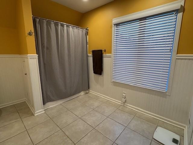 full bathroom featuring tile patterned floors, wainscoting, and curtained shower