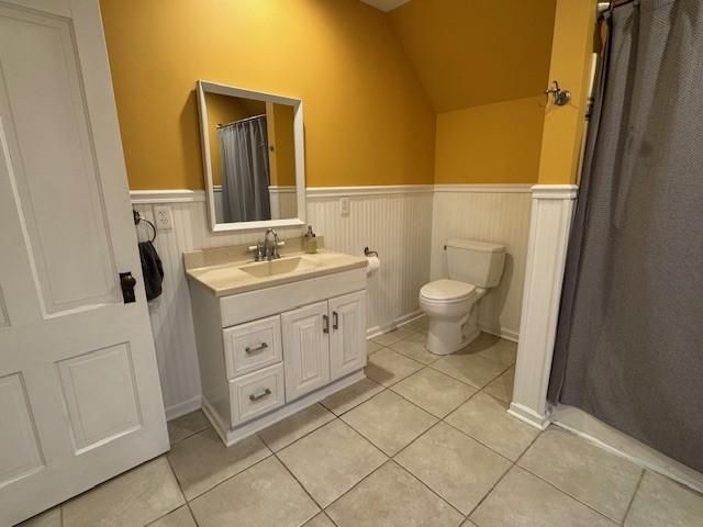 full bath with tile patterned flooring, a wainscoted wall, toilet, and vanity