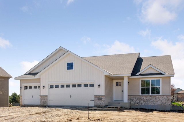 view of front of home with an attached garage, roof with shingles, and stone siding