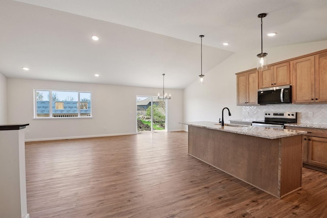kitchen with dark wood-style flooring, a center island with sink, tasteful backsplash, a sink, and stainless steel appliances