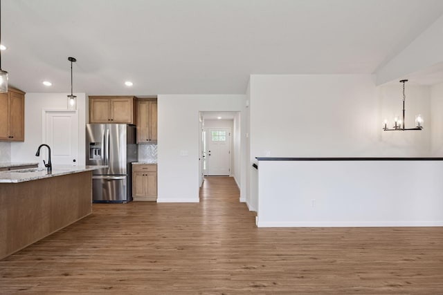 kitchen featuring decorative backsplash, wood finished floors, a sink, stainless steel fridge, and recessed lighting