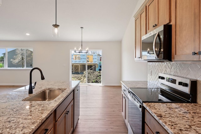 kitchen with light wood-type flooring, a chandelier, a sink, backsplash, and stainless steel appliances