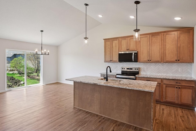 kitchen featuring wood finished floors, a sink, backsplash, vaulted ceiling, and stainless steel appliances