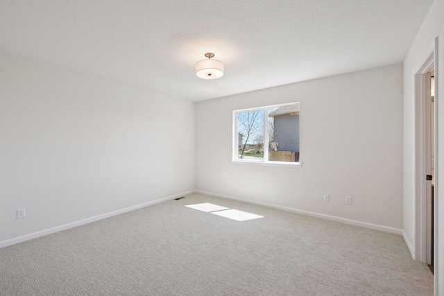 carpeted spare room with baseboards and a textured ceiling