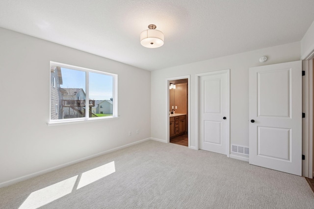 unfurnished bedroom featuring carpet flooring, baseboards, visible vents, and ensuite bath