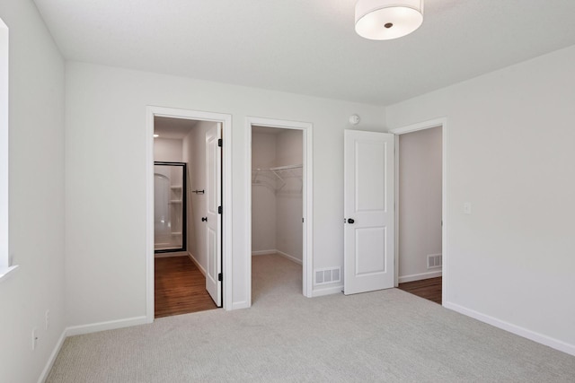 unfurnished bedroom featuring carpet floors, a walk in closet, a closet, and visible vents