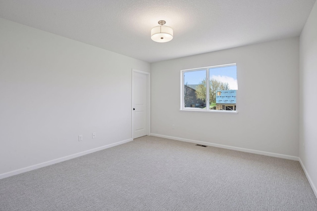 unfurnished room featuring baseboards, visible vents, and light carpet