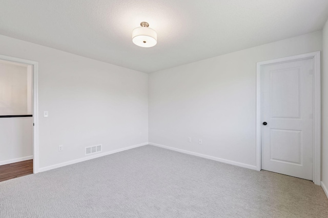 empty room featuring carpet flooring, baseboards, and visible vents