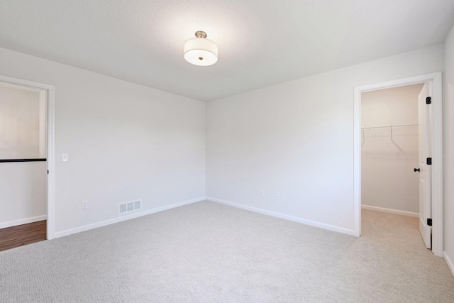 carpeted empty room featuring baseboards and visible vents