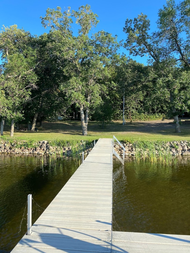view of dock with a water view and a yard