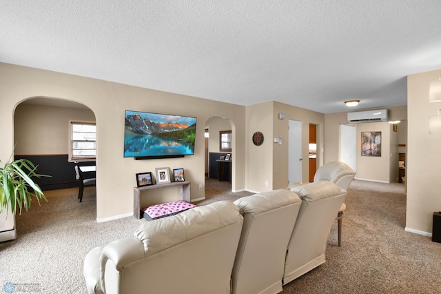 living area with arched walkways, a textured ceiling, a wall mounted AC, and carpet flooring