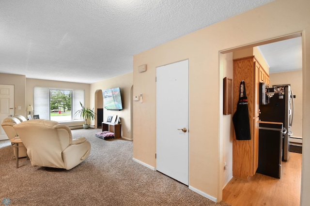living room with baseboards, a textured ceiling, baseboard heating, and light colored carpet