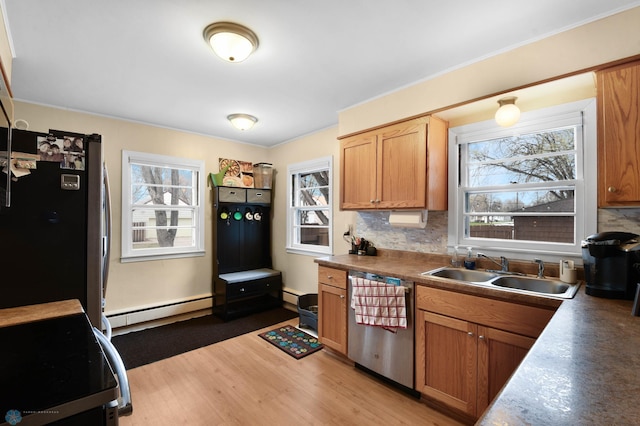 kitchen featuring a sink, baseboard heating, light wood-style flooring, stainless steel appliances, and tasteful backsplash