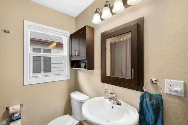 bathroom with toilet, curtained shower, and a sink