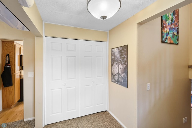 unfurnished bedroom featuring a textured ceiling, baseboards, light carpet, and a closet