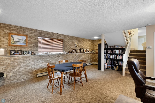 dining space with a textured ceiling, brick wall, and a baseboard heating unit