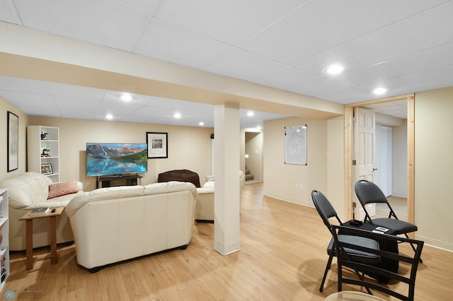 living area featuring light wood-style floors, baseboards, and a drop ceiling