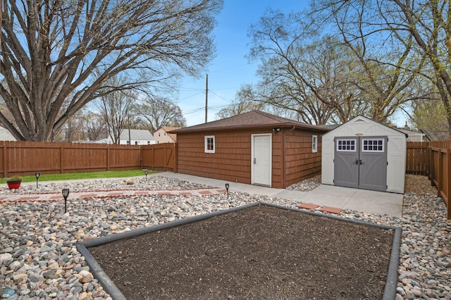exterior space with an outdoor structure, a fenced backyard, roof with shingles, and a patio