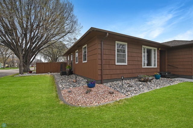view of property exterior with a lawn and fence