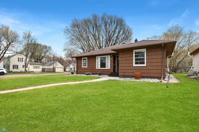 view of front facade featuring roof with shingles, a front yard, and a chimney