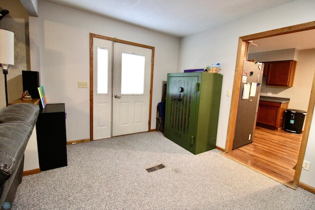 foyer featuring visible vents, baseboards, and light carpet