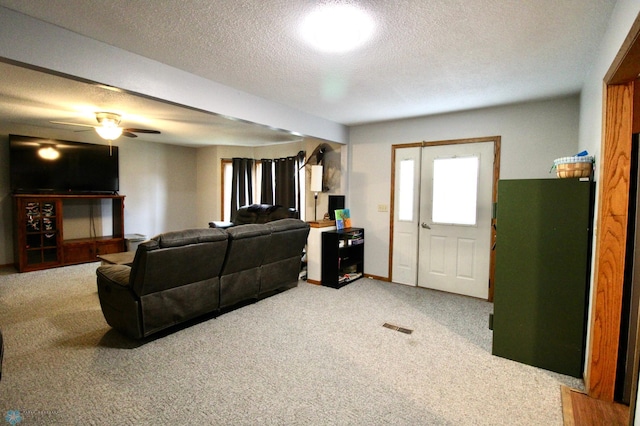 carpeted living room featuring a ceiling fan, a textured ceiling, and visible vents