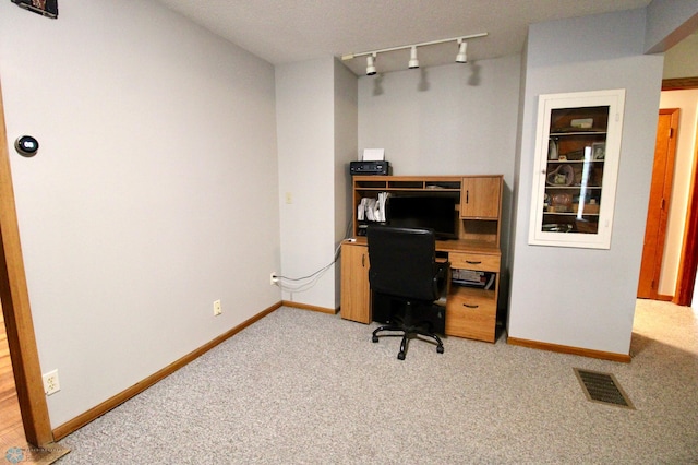office space featuring baseboards, visible vents, track lighting, and light carpet