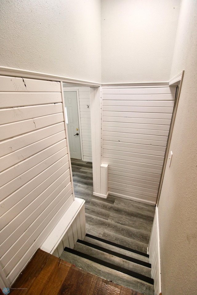 stairs featuring a textured wall and wood finished floors