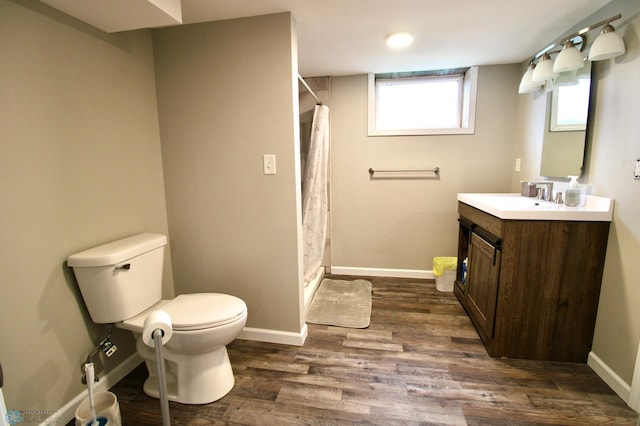 bathroom with vanity, toilet, baseboards, curtained shower, and wood finished floors