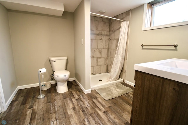 bathroom with baseboards, a stall shower, wood finished floors, and toilet