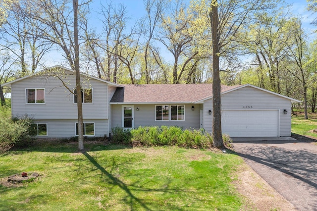 tri-level home with an attached garage, a front lawn, and driveway