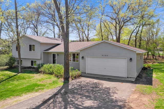 tri-level home with driveway, an attached garage, a front yard, and a shingled roof