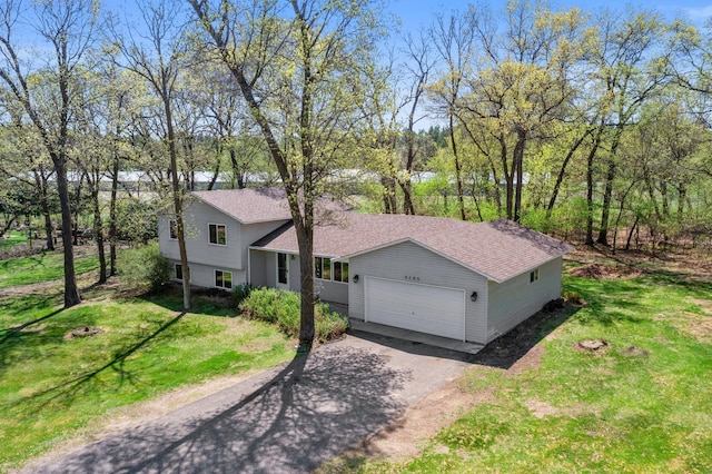 tri-level home featuring a garage, asphalt driveway, a front yard, and roof with shingles