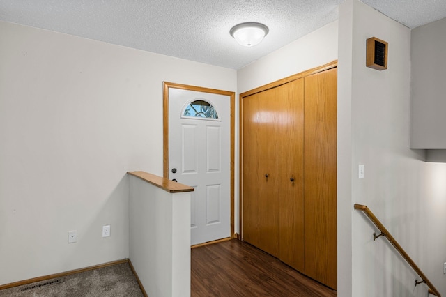 foyer with a textured ceiling, baseboards, and dark wood-type flooring
