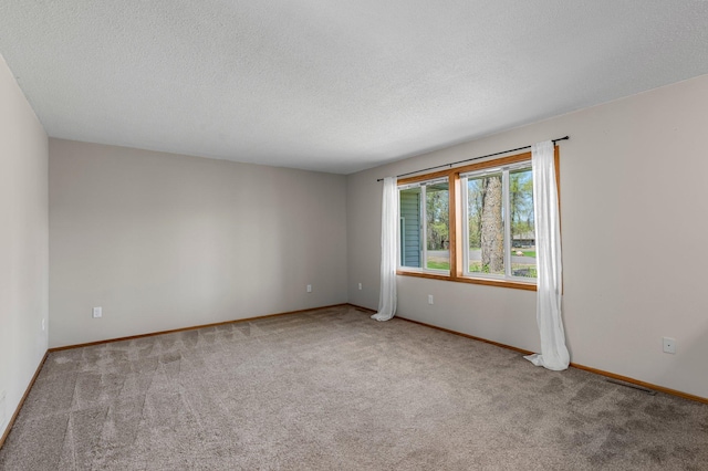 carpeted empty room featuring a textured ceiling and baseboards