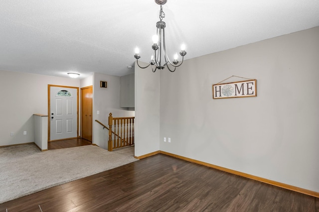 empty room with dark wood-style floors, a chandelier, and baseboards