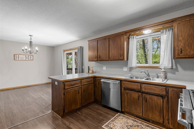 kitchen featuring dishwasher, a sink, a peninsula, light countertops, and decorative backsplash