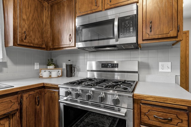 kitchen with stainless steel appliances, backsplash, light countertops, and a sink