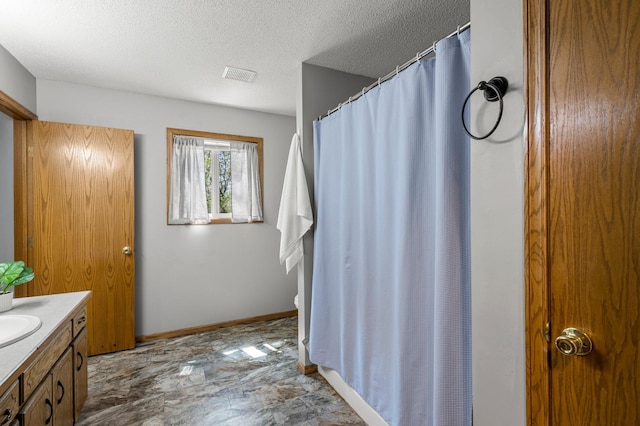 full bathroom featuring a textured ceiling, vanity, a shower with curtain, and baseboards