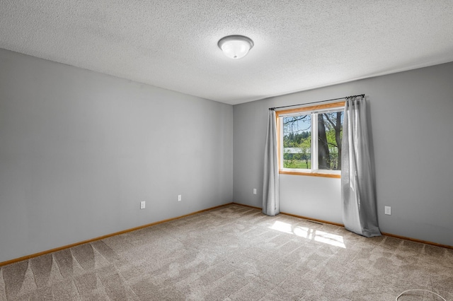 carpeted empty room featuring a textured ceiling and baseboards