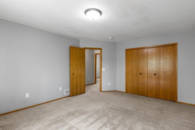 unfurnished bedroom with carpet floors, a closet, a textured ceiling, and baseboards